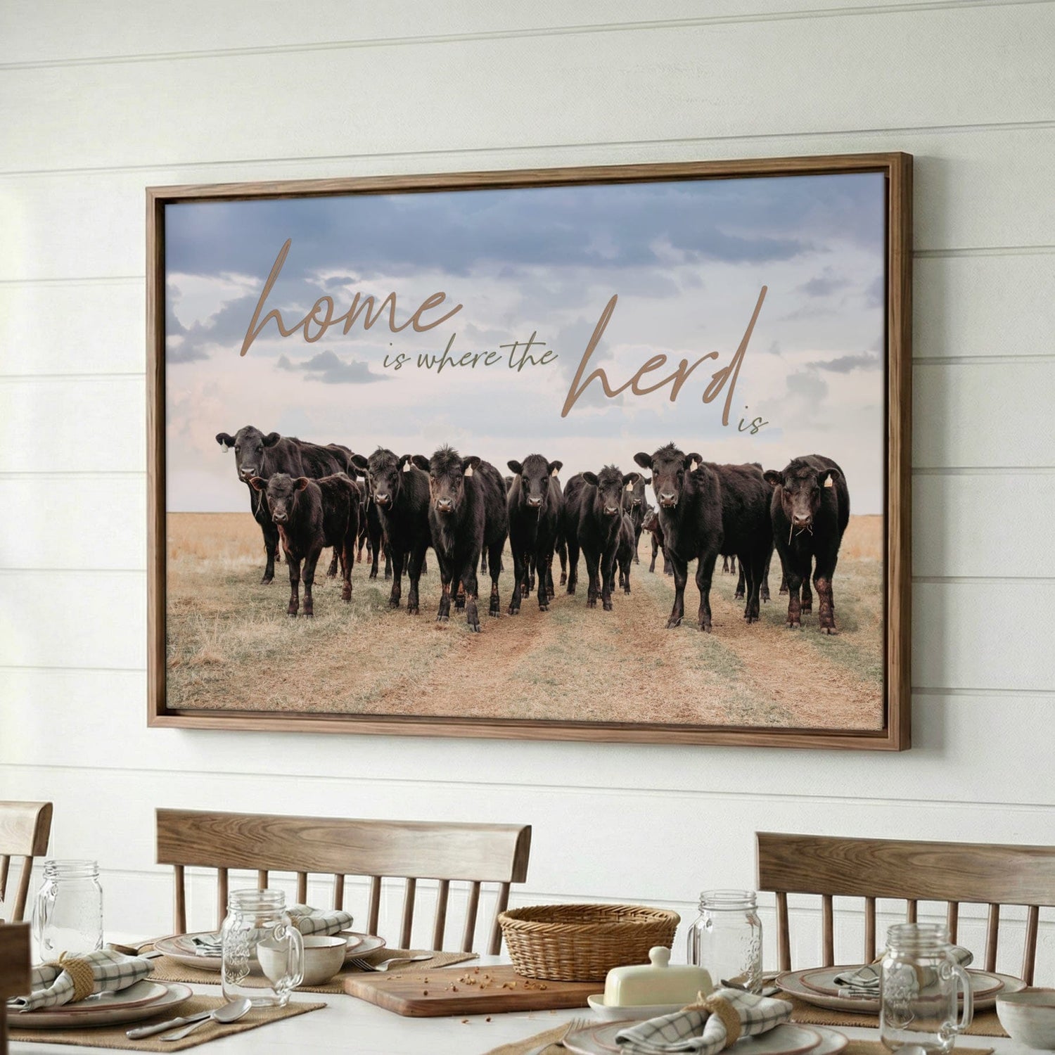 small herd of black angus cattle with text Home is Where the Herd is, float framed canvas on shiplap wall over a farmhouse dining table